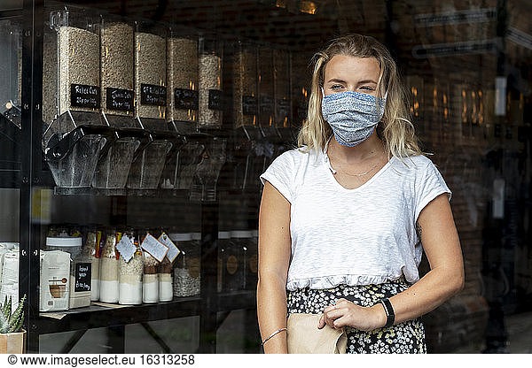 Woman wearing face mask shopping in waste-free local store  sustainability.