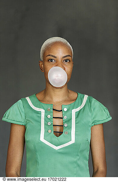 Woman wearing green dress making gum bubble