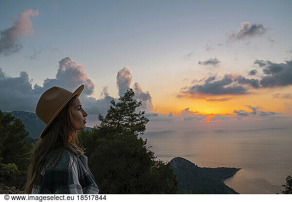 Woman wearing hat enjoying sunset at vacation