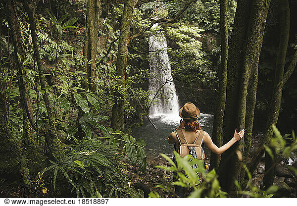 Woman wearing hat standing in front of waterfall
