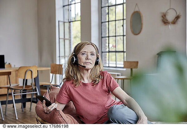 Woman wearing headset sitting in living room at home