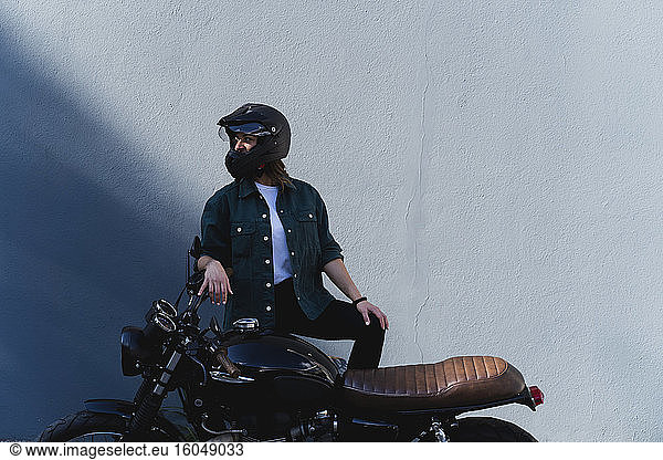 Woman wearing helmet standing at motorbike