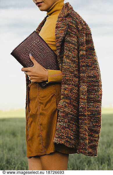 Woman wearing long coat holding vintage notebook