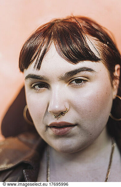 Woman wearing nose ring against wall