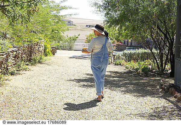 Woman wearing overalls walking in garden on sunny day