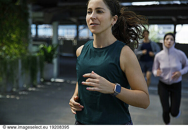 Woman wearing smart watch jogging with friends