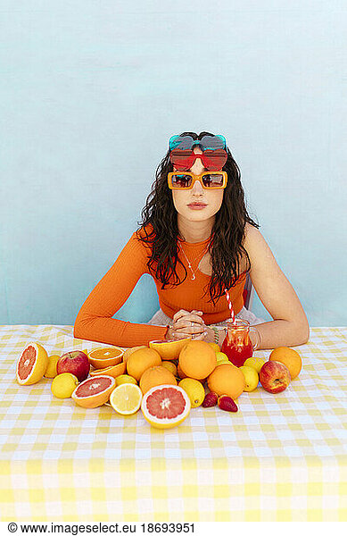Woman wearing sunglasses with different citrus fruits on table