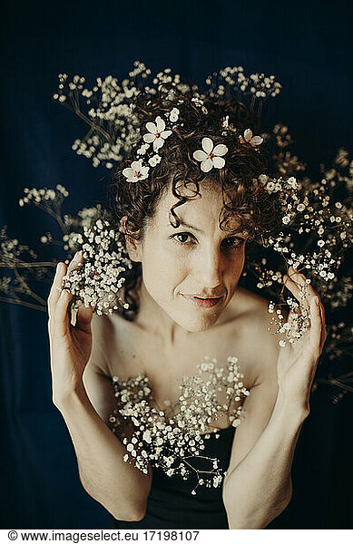 Woman wearing white flowers against blue background
