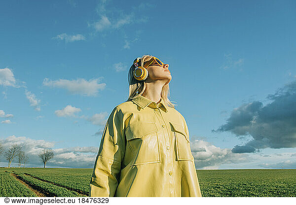 Woman wearing yellow shirt standing under blue sky