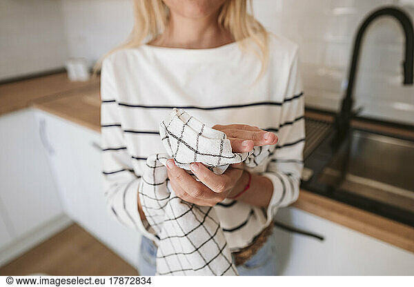 Woman wiping hands with napkin in domestic kitchen
