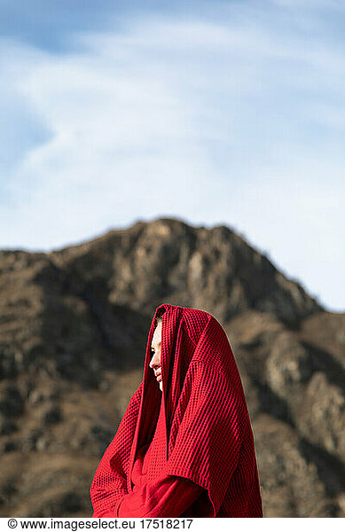 Woman with a bathrobe on the head on the head near the mountain