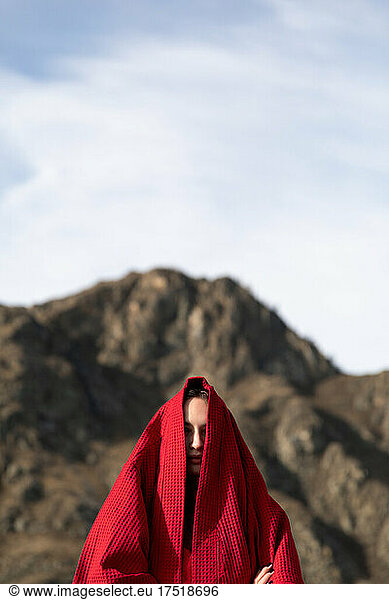 Woman with a bathrobe on the head on the head near the mountain