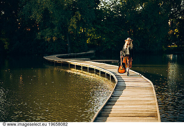 Woman with a guitar on the lake in autumn