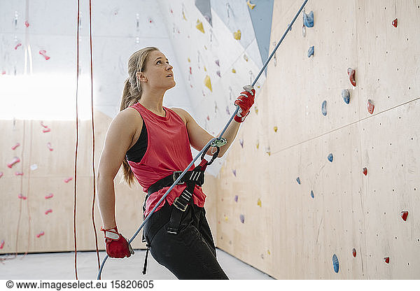 Woman with a rope securing partner on the wall in climbing gym