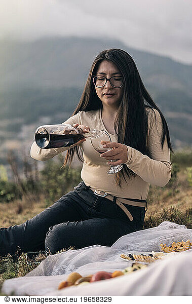 Woman with a wine bottle and cup in the hands over nature background