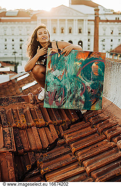 Woman with abstract art painting sitting on the roof