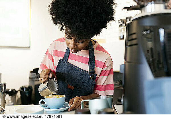 Woman with Afro hairstyle making coffee in cafe