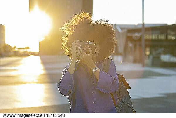 Woman with Afro hairstyle photographing through camera