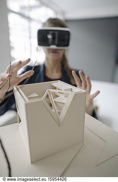 Woman with architectural model wearing VR glasses