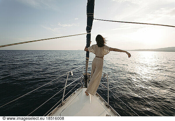 Woman with arm raised standing on sailboat