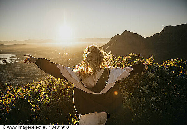 Woman with arms outstretched at sunrise