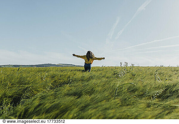 Woman with arms outstretched enjoying in meadow