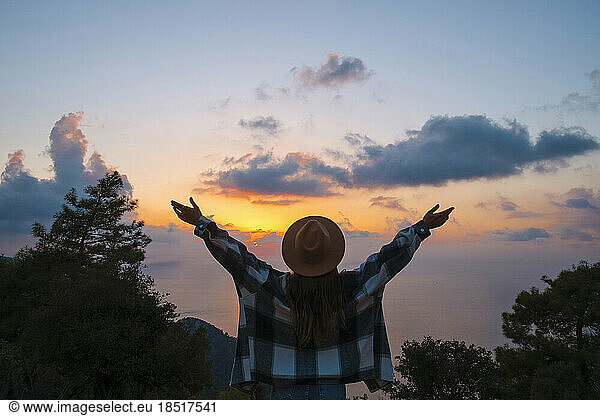Woman with arms outstretched enjoying sunset on vacation