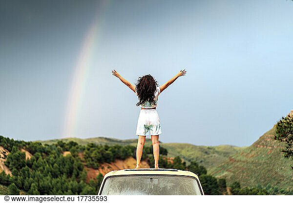 Woman with arms outstretched standing on van