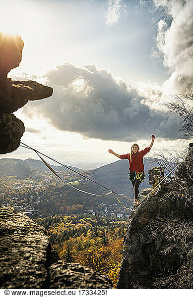 Woman with arms raised slacklining amidst mountains at Baden-Baden  Germany