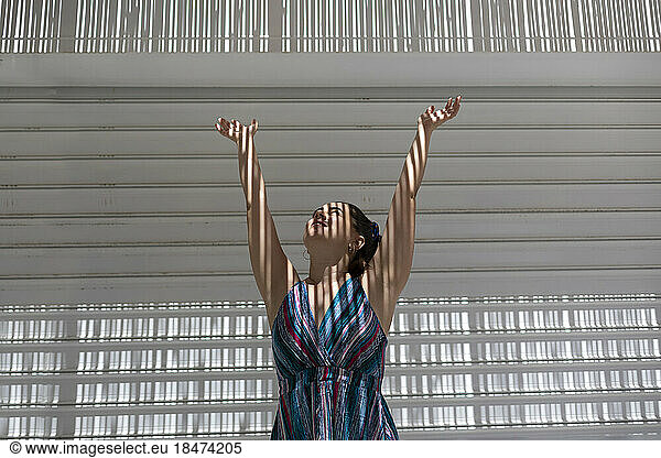 Woman with arms raised standing in sunlight