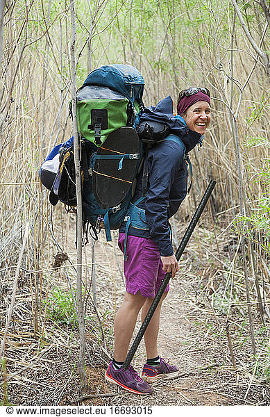 Woman with backpack with packrafting gear on Escalante River  Utah
