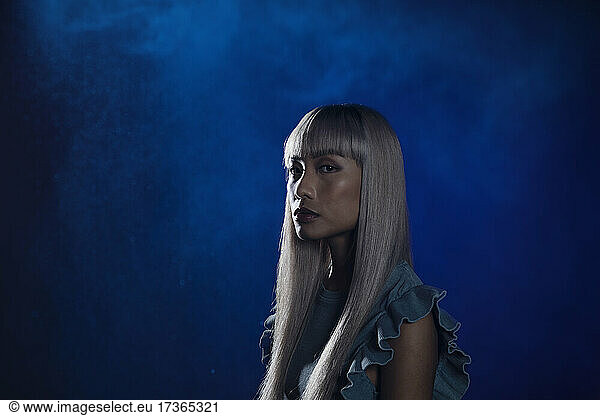 Woman with bangs staring against blue background