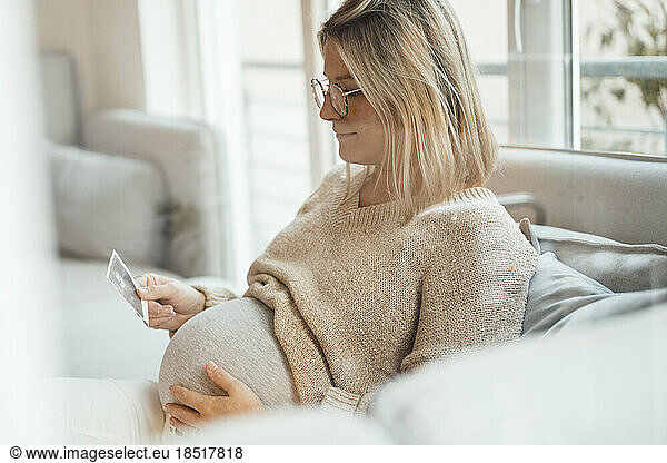 Woman with blond hair holding ultrasound photo at home