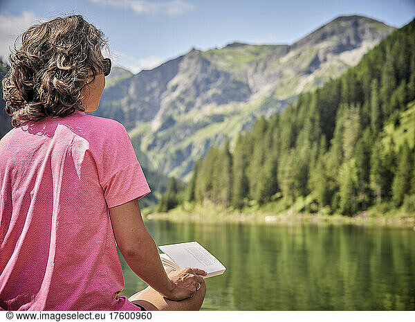 Woman with book looking at lake