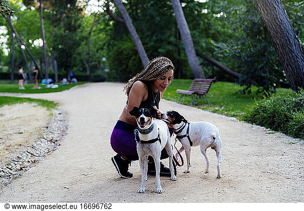 woman with braids playing with her dogs in the park