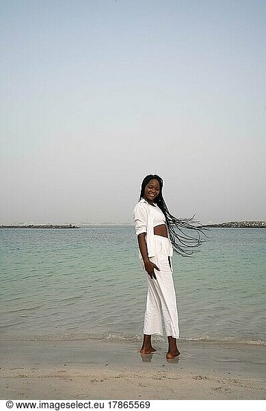 Woman with braids standing at the beach wearing white outfit