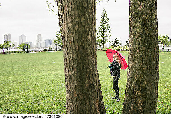 Woman with bright umbrella in green city park