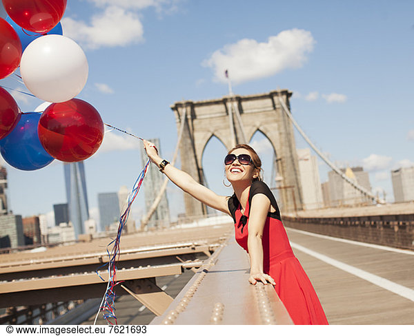 Woman with bunch of balloons on urban bridge