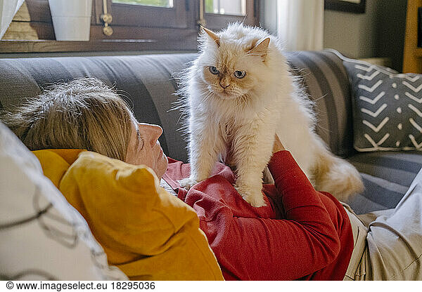 Woman with cat lying on sofa at home