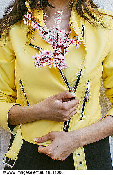 Woman with cherry blossom flowers tucked inside yellow jacket