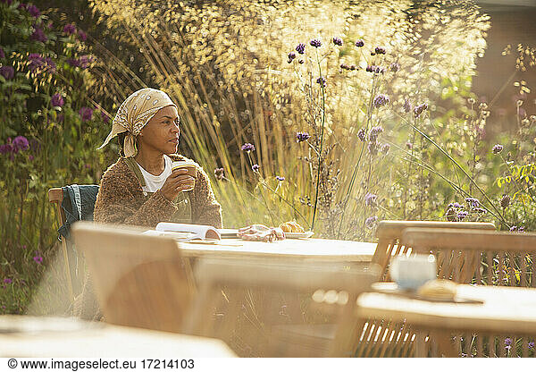 Woman with coffee at sunny idyllic garden cafe table