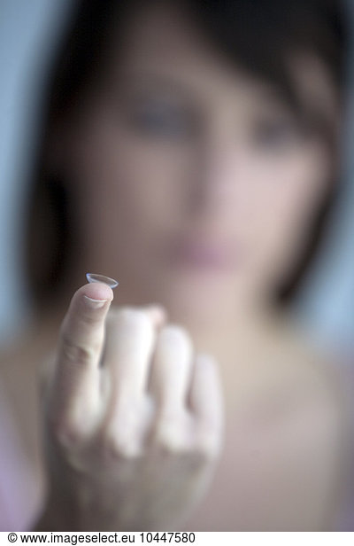 woman with contact lens on finger
