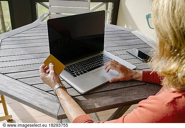 Woman with credit card doing online shopping through laptop at table