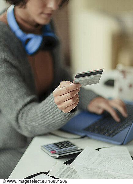 Woman with credit card paying bills online at laptop