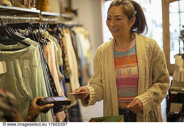 Woman with credit card paying shop owner with credit card reader