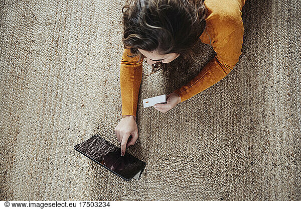 Woman with credit card using tablet PC at home