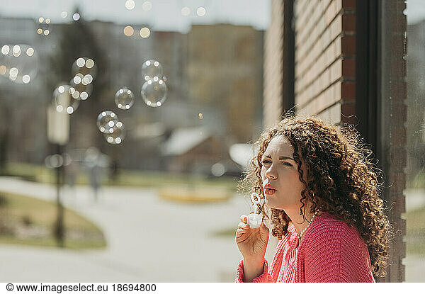 Woman with curly hair blowing soap bubbles