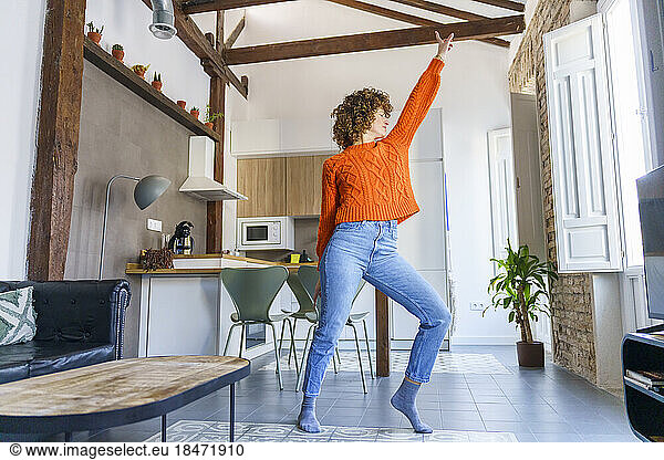 Woman with curly hair dancing at home