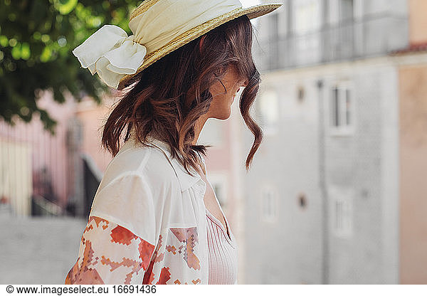 Woman with curly hair in a straw hat smiling  side view