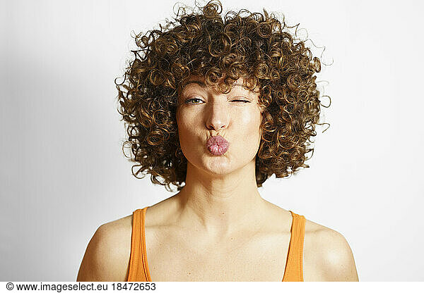 Woman with curly hair puckering face against white background